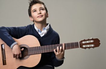 happy-boy-playing-with-pleasure-acoustic-guitar_186202-5657